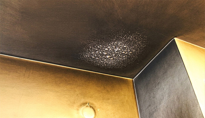 Condensation droplets forming on a dark ceiling corner