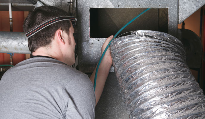 Technician cleaning duct