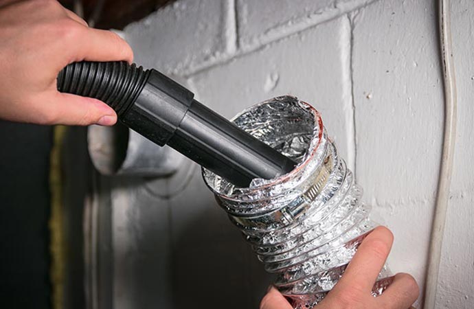 worker cleaning duct vent