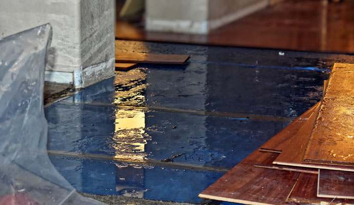 Hardwood flooring planks laid over a blue moisture barrier