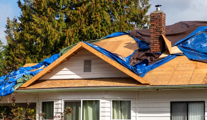 House roof covered with blue and brown emergency tarps