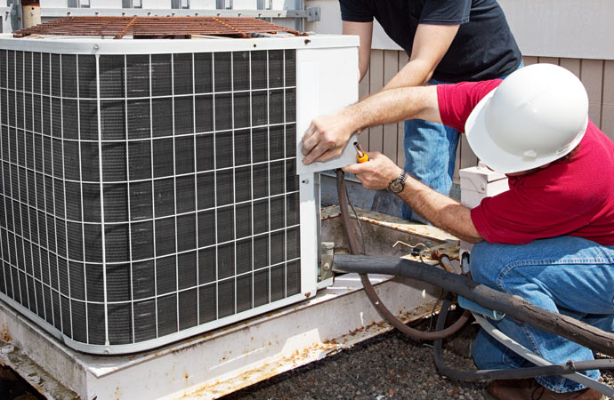 Professionals repairing a damaged AC unit.