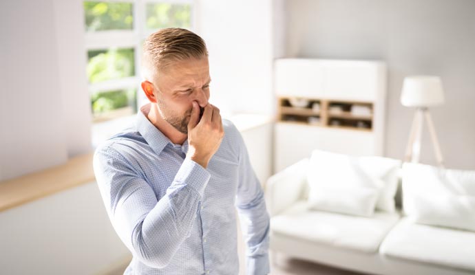 Man pinning nose for bad odor in living room