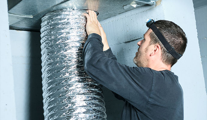 Technician attaching flexible foil duct to metal vent
