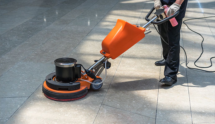 Technician cleaning commercial floor with buffer machine