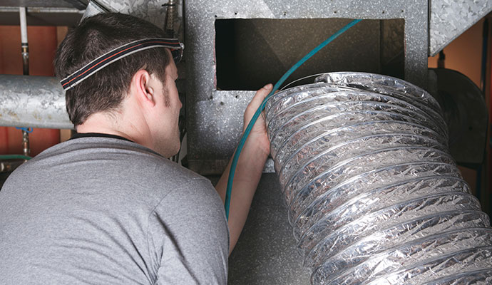 Technician cleaning an HVAC duct system with specialized equipment