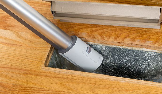 Vacuum attachment removing dust from an open floor vent