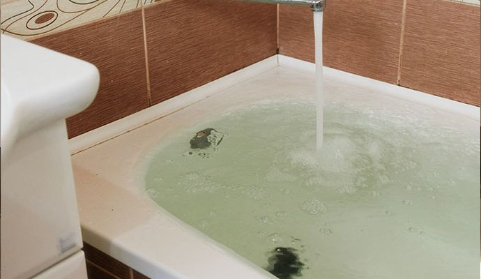 : Bathtub filled with water from open faucet Bathtub filled with water caused by an open faucet running continuously